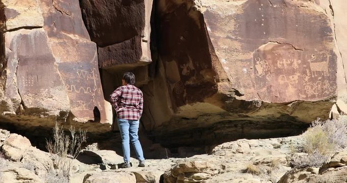 Woman admire explore ancient Indian rock art Utah. Vandalism bullet holes damage. Nine Mile Canyon, Utah. World’s longest art gallery of ancient native American, Indian rock art, hieroglyphs.