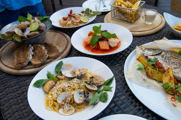 Many Food plate of Baked Scallop Mussel, Spaghetti Crap meat, Seabass fish with potato, Fried Chicken Fish Salad, Shrimp with cut salmon fried, arrange on table top view set up for photo shoot