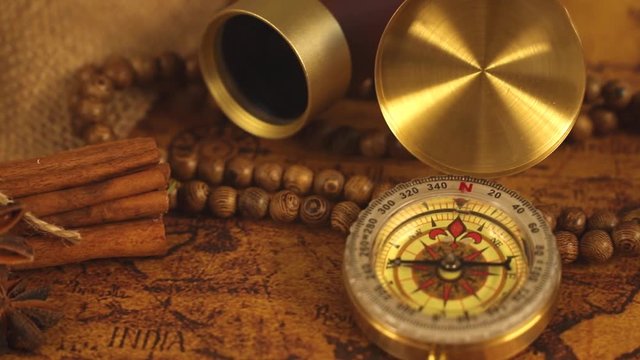 Vintage compass with spyglass telescope and cinnamon spices on an old world map - trade and explorer concept