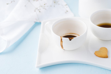 Empty cups of coffee and heart shaped cookie.