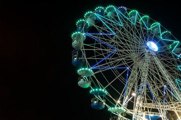 Colourful striped light illuminated spinning ferris wheel in motion moving at night.