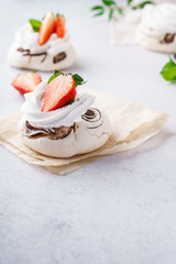 Pavlova meringue cakes with fresh berries on light background.