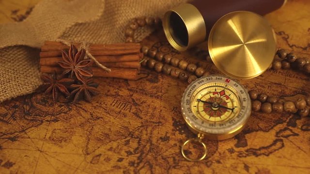 Vintage compass with spyglass telescope and cinnamon spices on an old world map - trade and explorer concept