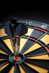 Three darts in bullseye of dartboard