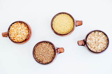 different types of groats in pots on a white background