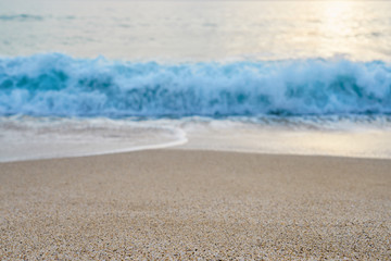   Sand on the beach close up with blurred sea and waves on a background on a sunset.