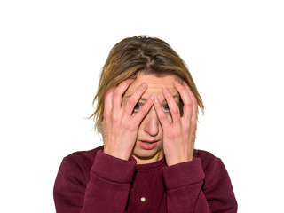 The woman in sweater covered her face with hands. She feels great fear. Girl isolated on white background.