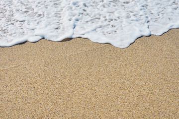 White foam on a sandy beach. Copy space.