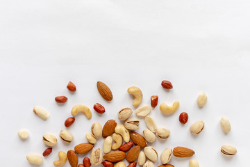 Assorted roasted and raw nuts scattered on white
