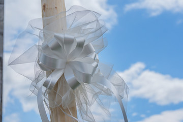 White loop fixed on wooden pilar as decoration for ceremony closeup.