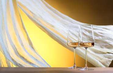 Glasses of white wine on a yellow background.