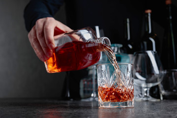 Barman pours whiskey in a glass at the bar.
