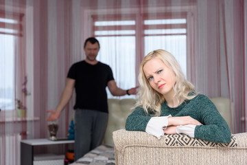concept husband and wife sit in a room and argue. The husband sits on the couch and the wife on the...