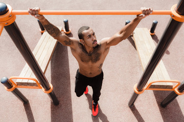Muscular man ready to do pull up exercises outdoors
