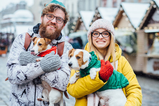 Funny hipster beard man and blond woman both in eyeglasses with their two Jack russel terrier dogs outdoor in winter city. Acquaintance, dog wedding, love at first sight, pets lovers concept.