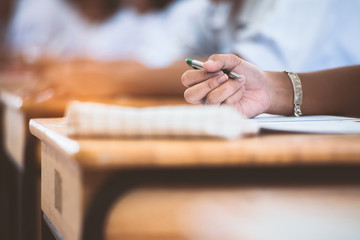 School students  taking exam writing answer in classroom with stress