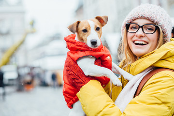 Close up of lovely young woman traveler in eyeglasses, yellow jacket, leather backpack warming his...