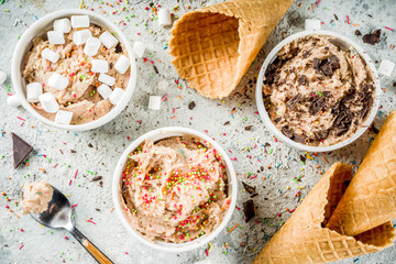Edible Raw Cookie Dough, sweet modern dessert, with waffle ice cream cones on grey stone background, copy space
