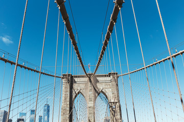 brooklyn bridge with american flag on clear blue sky and manhattan on background, new york, usa