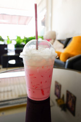 Strawberry milk pink shake / Iced pink milk in plastic cup and straw on table coffee shop