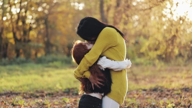 Cute little girl hugging her mother in the autumn park. Happy family concept