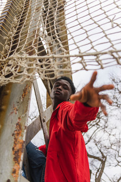 Young man reaching out, under volleyball net