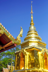 Fototapeta premium Thai pagoda covered with gold cut with blue sky. 