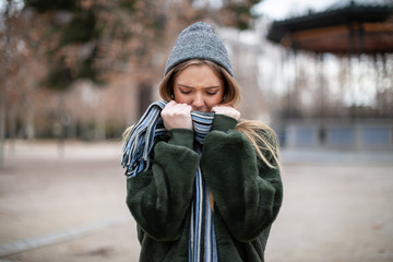 Young woman wrapping in scarf in autumn park