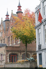 Fototapeta premium Tourists doing boat trip on canal of Bruges surrounded by flemish buildings in Belgium