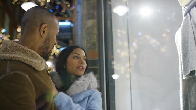 Young diverse couple browse a shop window at night in the city