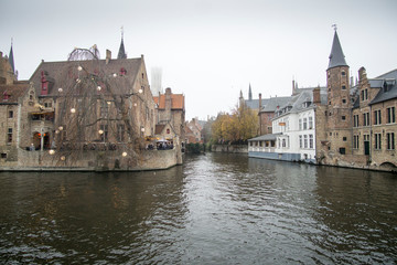 Obraz premium Tourists doing boat trip on canal of Bruges surrounded by flemish buildings in Belgium