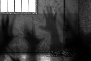 Gefängniszelle mit Händen als Schatten an der Wand