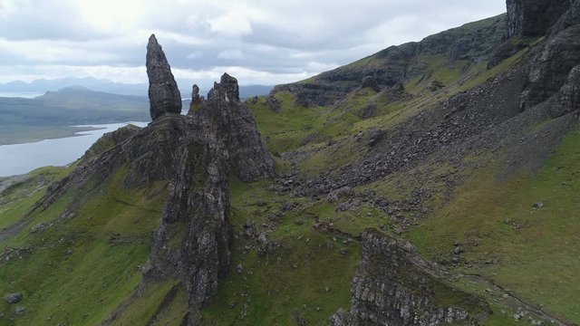 Drone flight past stark mountain landscape and Old Man of Storr, with wide panoramic view of Skye island, a popular tourist destination in Scotland