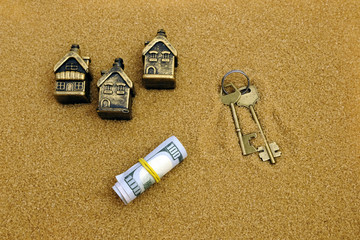 Money, houses, keys on the background of sand. Concept Use to describe sales, purchases, rental homes in warm countries.
