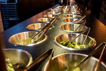 Bowls full of fresh vegetable ingredients for preparing salads in a restaurant.