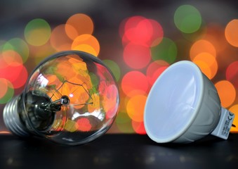 Incandescent lamp and LED lamp on the background of bright colored garlands