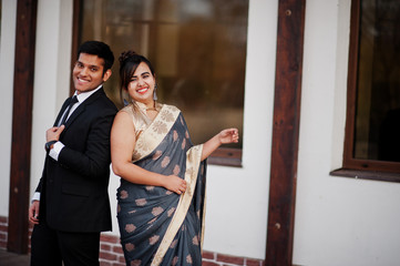 Elegant and fashionable indian friends couple of woman in saree and man in suit.