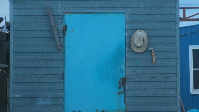 Concept of the cowboy lifestyle. Old blue wood door. Cowboy hat and knife near the door.
