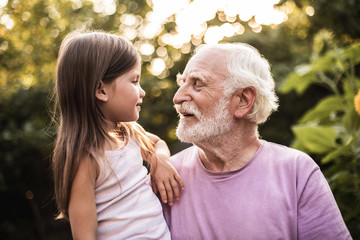 Fototapeta premium Granddaughter talking with her grandfather in park