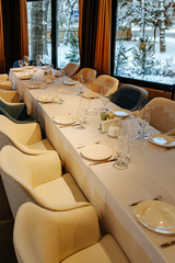 Tableware for new year banquet. Glasses, plates, fork, knife,served for dinner in restaurant with cozy interior. Wedding decorations and items for food, arranged by the catering service on large table