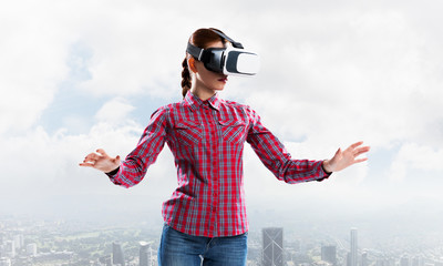 Girl in checked shirt wearing VR glasses experiencing another reality