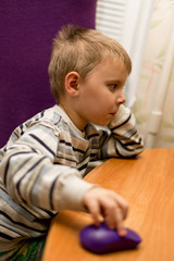 Naklejka premium Little boy at the table in front of the computer.