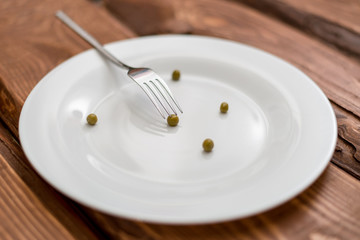 Diet concept. Several peas lying on a white plate. Restriction in nutrition.
