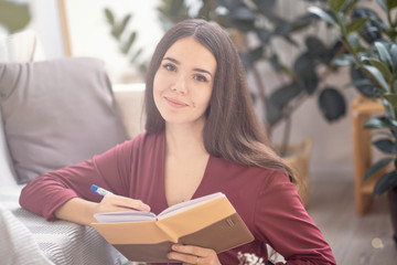 young girl sits on the floor in the early morning and writes in a diary or reads a book