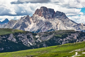 Mountain landscape with green meadow and two people in the foreground