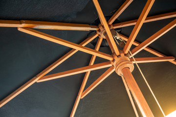 Crossing wooden umbrella structure create an abstract pattern on black