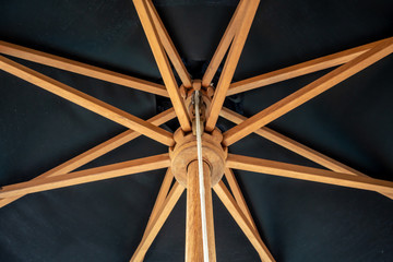 Crossing wooden umbrella structure create an abstract pattern on black
