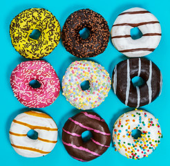 assorted donuts covered with eating, chocolate, nuts on blue background