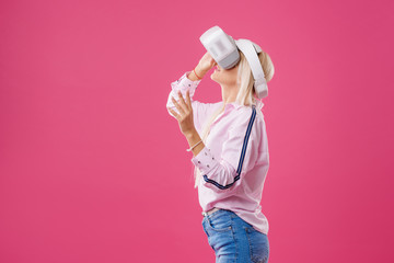 Young Blond happy woman student with virtual reality goggles. Studio shot on pink background. Virtual learning