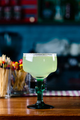 margarita cocktail closeup on bar counter in a margagita glass with lime